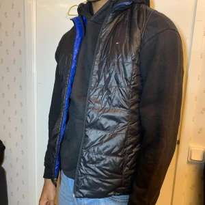 Tommy hilfiger väst - Säljer denna väst för att den är för liten för mig. Båda sidorna av västen kan användas och ena sida är svart medan den andra är blå! 
