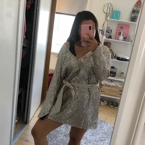 Hannalicious X NA-KD klänning - Silvrig glittrig klänning från Hannalicious X NA-KD i st. 34. Ganska oversized, då jag egentligen är 36-38! Passar liksom de flesta. Superfin, jag är sämst på knyta fint haha.  Använd bara 2 gånger. Nypris 900kr, säljer för 350kr. Frakt tillkommer!🤍