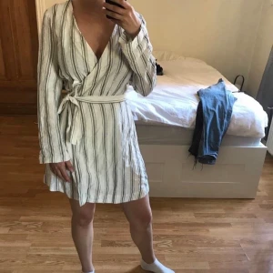 Omlottklänning i linne  - Skön och fin omlottklänning i linne från & other stories. Tyvärr har sömmen gått upp på ena ärmen men är lätt att laga eller så kavlar man bara upp ärmarna så syns det inte. Knappen i urringningen har också lossnat och fastnat på ena sidan. Fixas lätt.