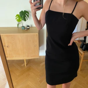 Svart klänning - Svart formsydd klänning med tunna straps. Köpt second hand, men känns som att den är skräddarsydd. Har innerfoder och dold dragkedja bak, slutar ovanför knä. Ca Strl xs/s. 