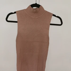 Ärmlös topp - En beige topp som sitter jättefint och anpassar sig efter kroppsform. Strl M men tror även att den passar S. Fint skick i övrigt. Frakt ingår! 