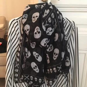  - En tunn och skön sjal från Gina Tricot i svartvitt med dödsskallar. Gott skick, gå ggr använd. 