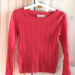  - Ribbad, korallröd, tunnstickad tröja. Står xxs men uppskattar den till en XS. Fin skurning i kragen.