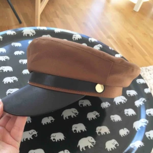  - Skepparmössa i brunt med gulddetaljer  Helt ny, använd en gång. Ren, fräsch, djur- och rökfritt hem. 