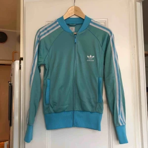  - En tracktop från Adidas. Storlek 36/small, damstorlek. Skick: 6/10 (en mindre fläck, se bild 2. Ska försöka få bort den). Levereras nytvättad. Finnes på Södermalm, Stockholm. Kan postas men då står Du för frakten, (54kr). Mvh Marija & Nugget