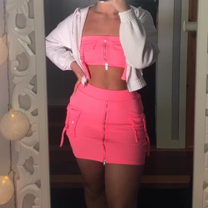 Neonrosa set - Jätte snyggt neonrosa set från Fashion Nova, kjolen är använd en gång och toppen är helt oanvänd. Dragkedjorna går att dra upp och det finns även som en säkerhetsnål i toppen för att hålla dragkedjan nere. Du som köper betalar frakt.