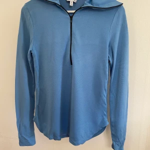 &otherstories zip polo - Ljusblå &othersstories polo med dragkedja i träningsliknande material. Fint skick, använd fåtal gånger.