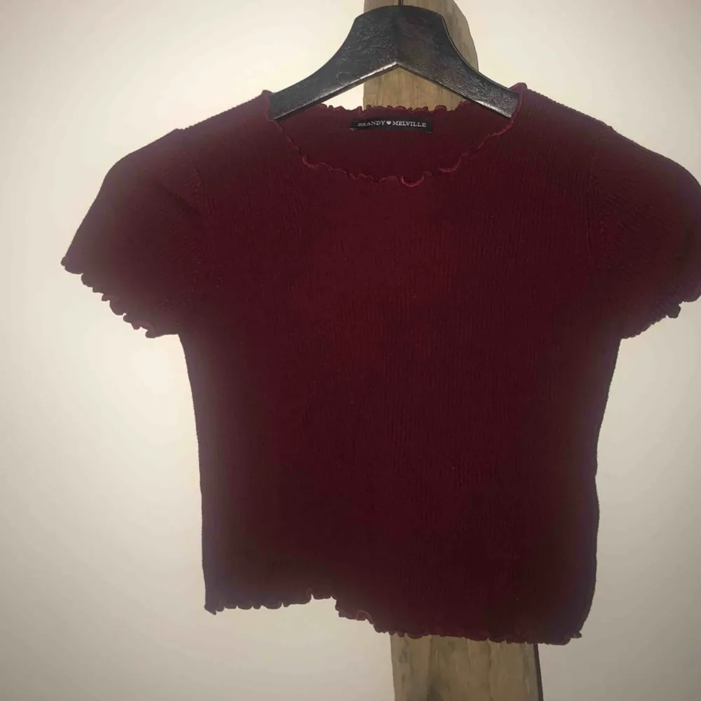 Croppad vinröd ribbad ljuvlig tröja från Brandy Melville 🥀   Ser ut dom det är en fläck på tröjan men det är det inte, ngt knas med ”ribbningen” som gör att det blir så. SKICK: Ett hål på vänster sida längst ner, lätt att sy (se bild). Toppar.
