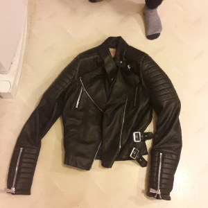 Chiquelle skinnjacka svart - Dett är en svart skinnjacka i storlek 38/S storleken är liten så det är som xs och priset kan diskuteras,den har ett litet hål på insidan som inte märks. Ny pris 699 kr.