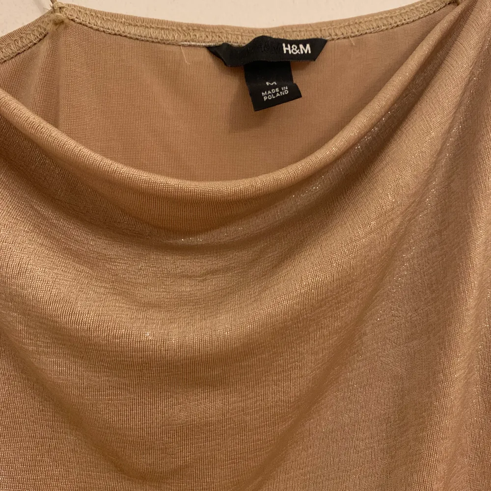 En guldig topp från H&M i cowlneck modell. Toppen är i fint begagnat skick. Storlek M/Medium.. Toppar.