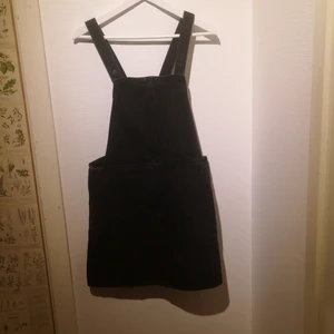 Svart jeansklänning från monki  - Jeansklänning i hängslemodell. Svart i storlek 40 (M). 