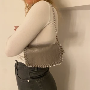 Axelremsväska  - Grå axelremsväska från Tiamo, knappt använd. Frakt tillkommer 🚚 