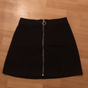 Svart jeanskjol - Svart jeanskjol med dragkedja på framsidan. 