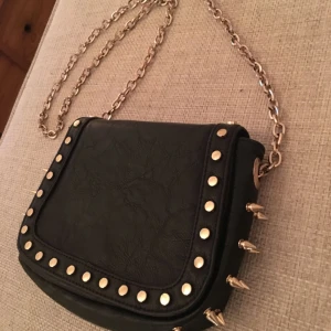  - En svart fake-läderväska från Mango med guldnitar. Gott skick. 