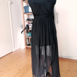  - Svart klänning med slit i kjolen. Jag har ingen aning var den kommer ifrån och om den varit använd. 