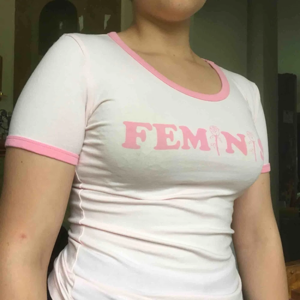 Ljusrosa t-shirt, slim fit. Tryck på bröstet: Feminist. Nyskick. . T-shirts.