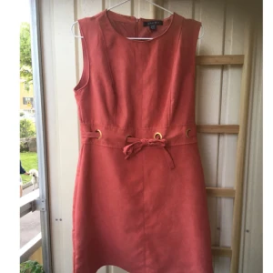  - Klänning i rostfärg. Fina detaljer och snygg modell. Dragkedja bak. 