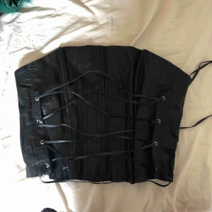  - Svart korsett i glansigt tyg och läderliknande snören🔥