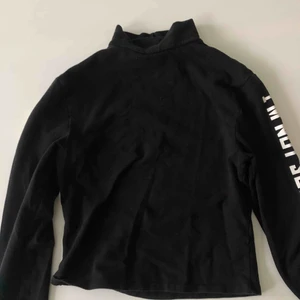 - En croppad svart tröja , använt ett fåtal gånger , väldigt bra skick, i båda armarna är det vit text , den har även en halv polo krage 