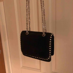  - Mocka väska i mörkblå/svart. Den är liten med en lång kedja som man antingen kan ha över kroppen eller om man ”tar upp” kedjorna så det blir mer av en axelväska. Passar fint till vardag och fest. Bra kvalite, köpt för 600kr från början 