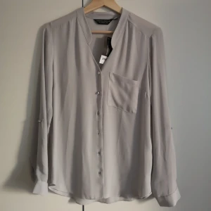  - Helt ny oanvänd blus! Superfin i ljust grå med silverdetaljer 😍👌 I priset ingår frakt! 