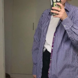 Skjorta - Blå och lila skjorta med liten inbrodering på nedre höger sida. Köpt på second hand men är i utmärkt skick, själv har jag använt den lite men säljer nu då den sällan kommer till användning. Frank inkluderat i pris.