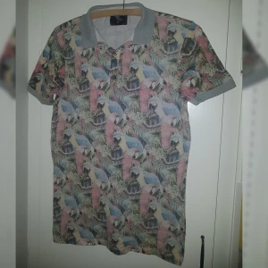 pike tröja - Piké tröja från Cedar wood state med pastell papegojor! Herrtröja men kan likaväl användas av kvinnor. Jag gillar den men får inte användning av den, i bra skick!