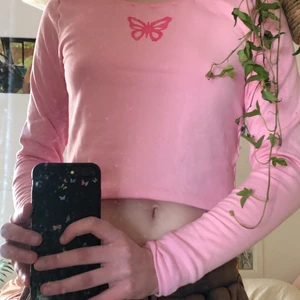 Rosa y2k tröja med fjäril, stl M - Hemmagjord långärmad tröja i supermjukt trikåtyg. Målad rosa fjäril på bröstet. Den är ksk liiiite större än en M, iaf i armarna. Pga strul med symaskinen är många av sömmarna ganska ”bubbliga”. 