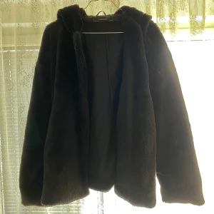 Faux fur jacka  - Gosig svart faux fur jacka med en härligt stor luva! Varan har inga defekter och är fortfarande glansig trots mycket användning! Storleken är L, men passar mig som XS väldigt bra som oversized! Läs gärna mina villkor! 💓🧚🏼