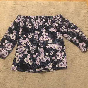 Bra skick av en blommig off-shoulder tröja med lila blommor i blåa och svarta nyanser
