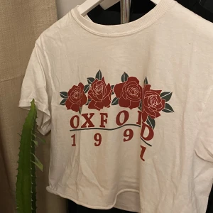 T-Shirt crop top - 100kr med frakt. Perfekta vita t-shirten som ändå ger lite form. Funkar att ha med trycket fram men går också att vända den ”bak och fram” och ha vit framsida och tryck i ryggen. RECOMEND! Storleken är ONESIZE men skulle säga XS/S. Trycket: Oxford 1991 