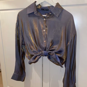 Skjorta - En sjukt snygg skjorta från shein, den är gråblå med ett guldfärgad lager när man riktar blixt eller någon form av ljus mot skjortan syns guldet ännu mer, skjortan han du vika, knyta som du vill det är en lite oversize skjorta som du kan justera