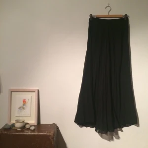  - Genomskinlig svart, veckad långkjol. Saknar lapp, men skulle gissa att det är en S. Har haft en innerkjol men den är bortklippt. Frakt tillkommer. 