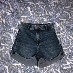 Shorts Storlek 34 - Mörkblåa högmidjade shorts i storlek 34, köpte för 1 år sen och använt cs 2-5 gånger, du står för frakten!