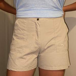 Ett par beiga högmidjade shorts. Det står att de är i storlek 42 men passa på modellen som oftast har storlek 38. Köparen står för frakten.