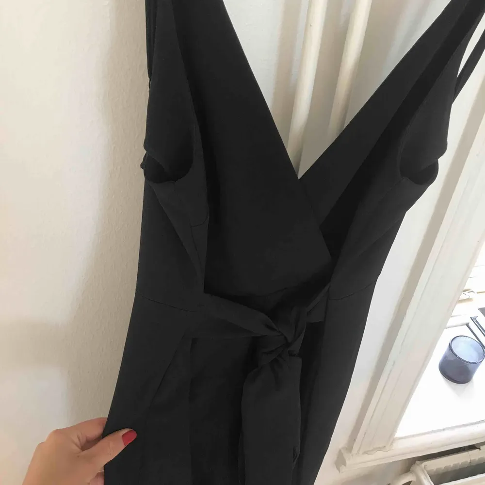 Jumpsuit med långa ben i svart från Asos!  Storlek 34, knyte i midjan. Aldrig använd. Köparen står för frakten . Klänningar.