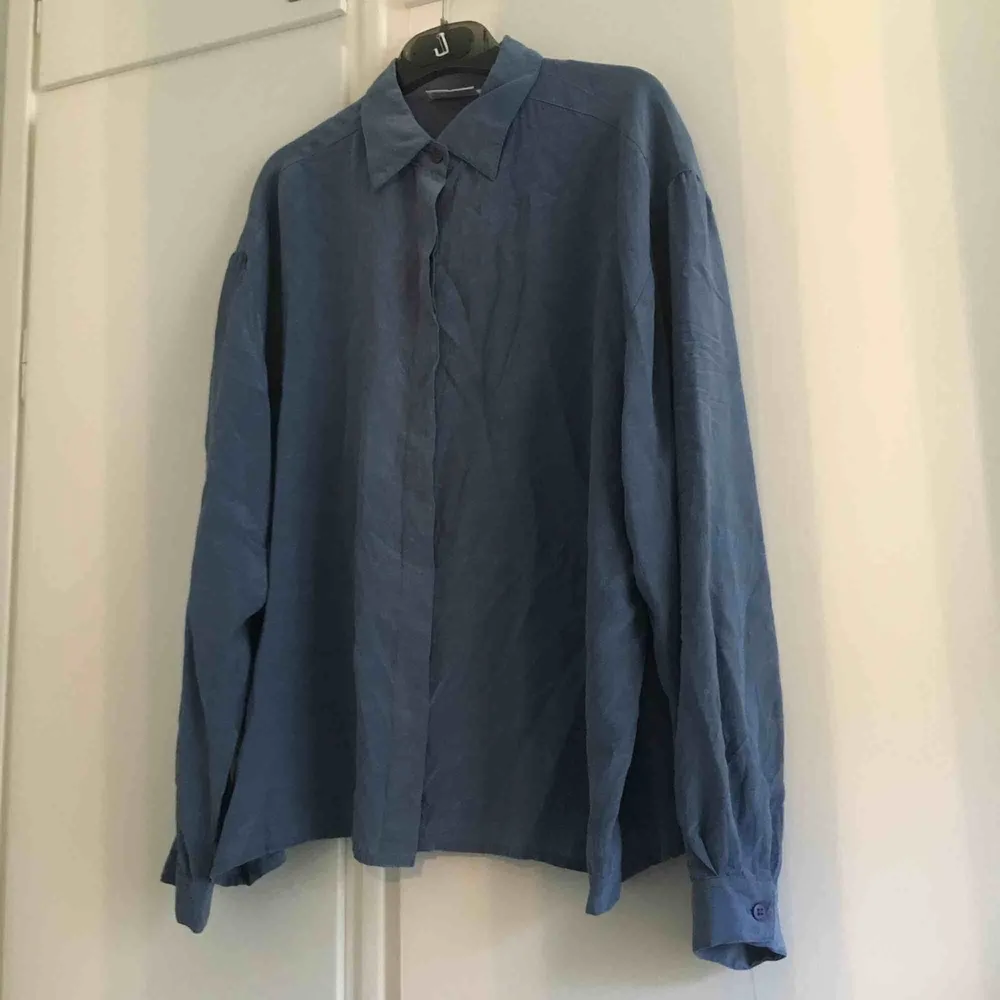 Dimblå blus köpt second hand. 100% silke. I bra skick. Märkt storlek 42, passar mej oversized som är en 36a.. Blusar.