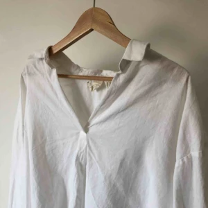  - Vit skjorta i linneaktigt material, den är tyvärr lite kasst uppsydd längst ner därför det låga priset!