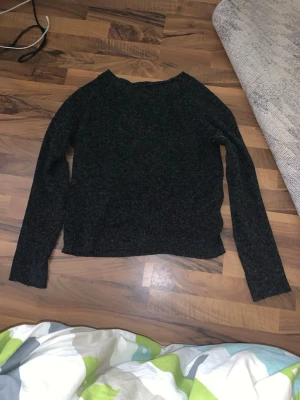 Mörkgrå stickad tröja - En enkel och stilren mörkgrå stickad tröja med rund hals och långa ärmar. Tröjan har en rak passform och är gjord i ett mjukt stickat material som passar perfekt för kyliga dagar.