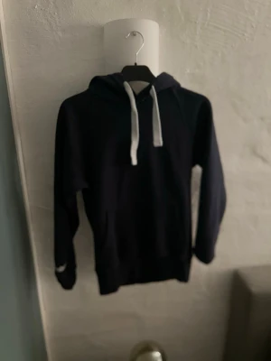 Russemerch hoodie mörk blå - En stilren mörkblå hoodie med vita snören. Perfekt skick och inga hål eller liknande. Storlek S och sitter och matchar bra till alla jeans/byxor. Riktigt snygg och skön hoodie.