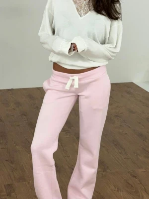 Ljusrosa mjukisbyxor russemerch  - Säljer ett par ljusrosa mjukisbyxor med bred resår i midjan och vit dragsko, som liknar russemerch. Byxorna har raka ben och är tillverkade i ett mjukt, bekvämt material som passar perfekt för chill dagar. Har en lagad defekt på baksidan.