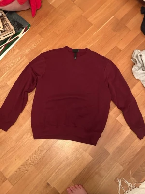 Vinröd crewneck sweatshirt - En oversized vinröd crewneck sweatshirt med rund hals och långa ärmar. Tröjan har ribbade muddar vid ärmslut och nederkant.