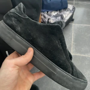 Svarta slip-on sneakers i mocka - Stilrena svarta slip-on sneakers med ovandel i mjuk mocka och tjock sula i gummi. Skorna har minimalistisk design utan snörning och en låg siluett som passar till många olika outfits.