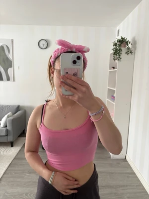 Rosa ribbad croppad linnetopp - Säljer en ljusrosa croppad linnetopp med smala axelband och ribbad struktur. Toppen är ärmlös och har en enkel, stilren design som passar perfekt till jeans eller kjol. Superfin färg och skön passform!