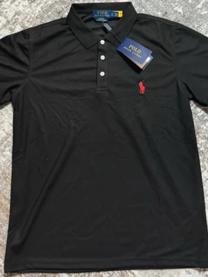 Svart pikétröja Polo Ralph Lauren - Säljer denna feta Ralph Lauren shirten i storlek M, sitter väldigt bra på💯 väldigt feta inför sommaren, passa på att köpa🌟 T-shirten är i fint skick och säljs pågrund av att jag behöver pengar🙌🏻 hör gärna av dig vid frågor eller snabb affär🕺