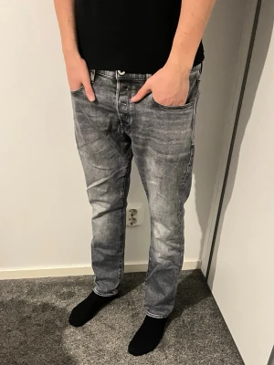Grå slim fit jeans från G-Star RAW - Snygga grå slim fit jeans från G-Star RAW. De har gått sönder emellan byxorna som man ser på den tredje bilden men är fixat och ser knappast det. Storleken på jeansen är 32W och 30L. Modellen på bilden är 188cm lång och väger 74kg