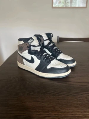 Nike Air Jordan 1 High svart/vit/brun - Säljer ett par Nike Air Jordan 1 High sneakers i svart, vitt och brunt. Storlek 42,5