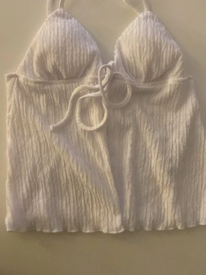 Sommar tröja - Supersnygg vit bikiniöverdel i ribbad struktur med trekantskupor och knyt framtill. Perfekt för sommaren och stranden. Materialet känns mjukt och följsamt, och modellen ger en trendig look.