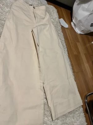 Beige raka chinos från zara - Snygga beige chinos från zara med rak passform och klassisk design. Byxorna har knapp- och dragkedjestängning samt diskreta sidfickor. Perfekta för en clean och stilren look.
