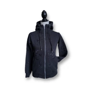 Hoodie med döskallar - Broderade döskallar över hela. Två fickor.